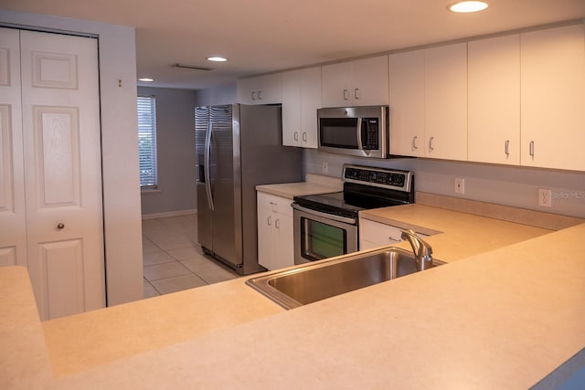 kitchen featuring light tile patterned flooring, appliances with stainless steel finishes, sink, and white cabinets