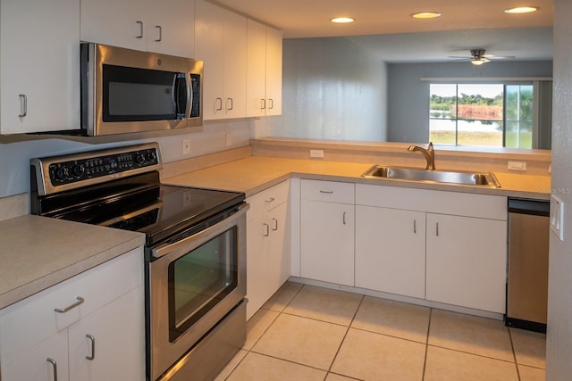 kitchen featuring sink, ceiling fan, appliances with stainless steel finishes, white cabinetry, and light tile patterned flooring