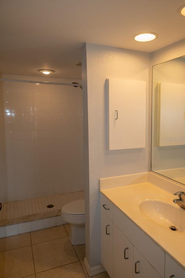 bathroom with tiled shower, vanity, toilet, and tile patterned flooring