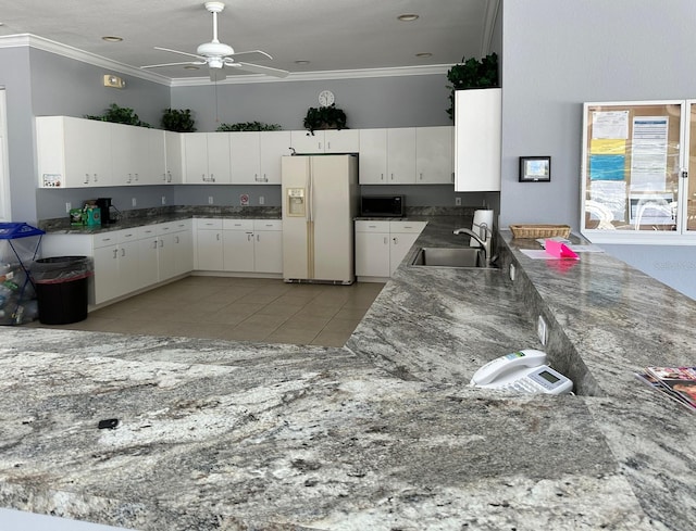 kitchen featuring sink, white cabinets, ornamental molding, white refrigerator with ice dispenser, and light tile patterned floors