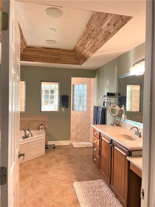 bathroom with vanity, a bathtub, tile patterned floors, and a tray ceiling