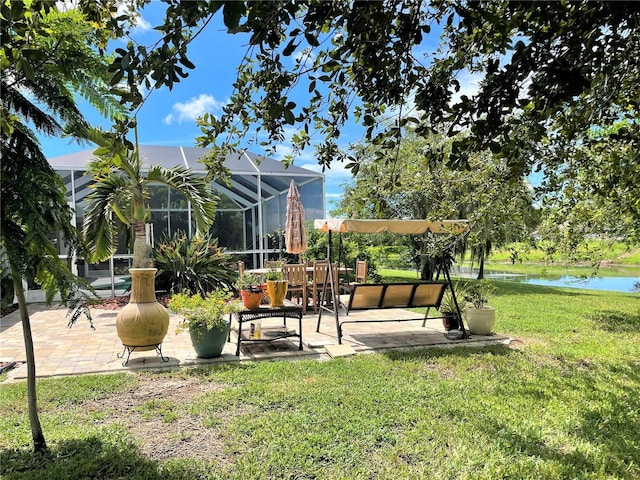 view of yard with a patio, a water view, and glass enclosure