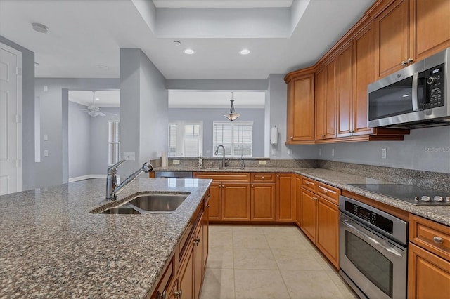 kitchen with light tile patterned flooring, stainless steel appliances, sink, and dark stone countertops