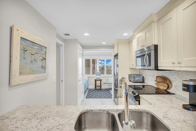 kitchen featuring light stone countertops, backsplash, sink, and stainless steel appliances