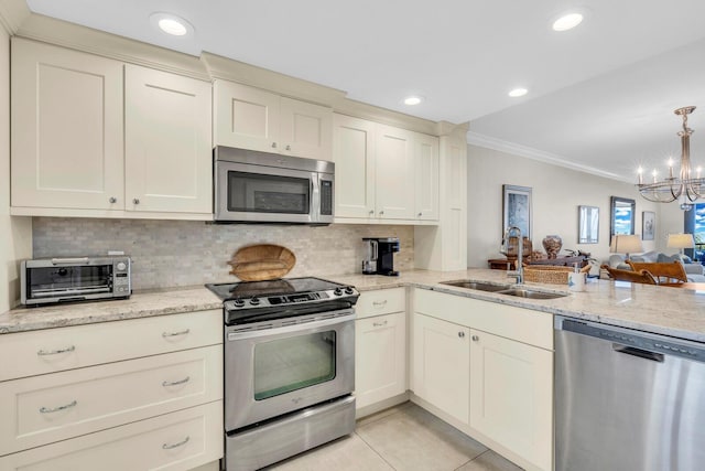 kitchen with light tile patterned floors, cream cabinetry, stainless steel appliances, a notable chandelier, and sink