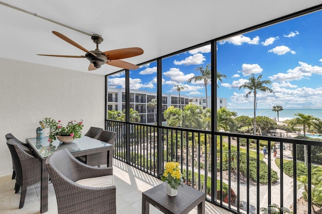 sunroom / solarium featuring ceiling fan, a wealth of natural light, and a water view