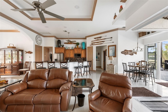 living room with ceiling fan, a raised ceiling, crown molding, and a towering ceiling