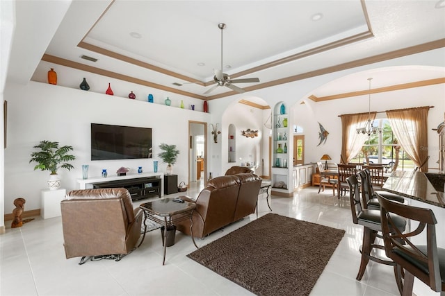 tiled living room with ceiling fan with notable chandelier, a raised ceiling, and crown molding