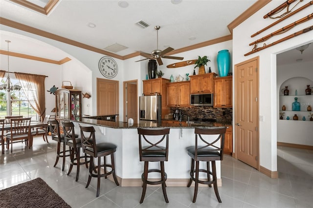 kitchen with a kitchen island, built in features, light tile patterned flooring, and appliances with stainless steel finishes