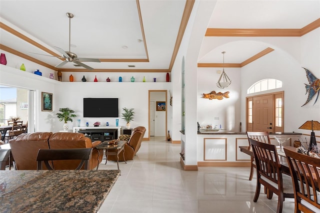 living room featuring ceiling fan, light tile patterned floors, ornamental molding, and a towering ceiling