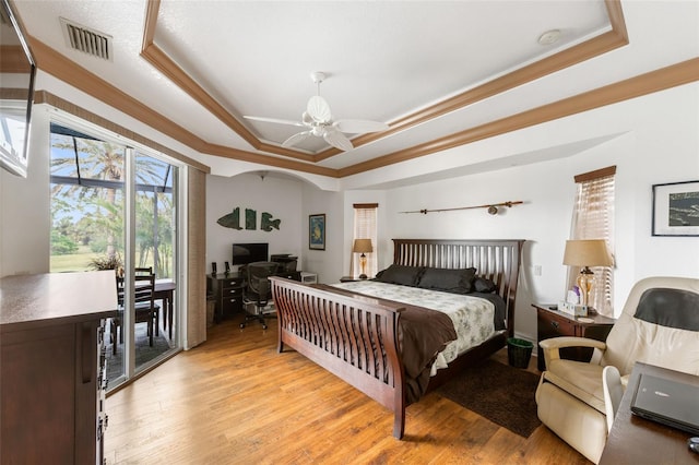 bedroom featuring light hardwood / wood-style flooring, ceiling fan, a raised ceiling, access to exterior, and ornamental molding