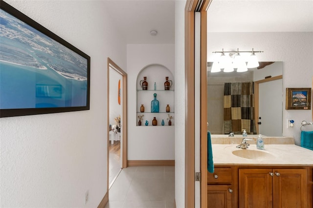 bathroom with built in shelves, walk in shower, vanity, and tile patterned flooring