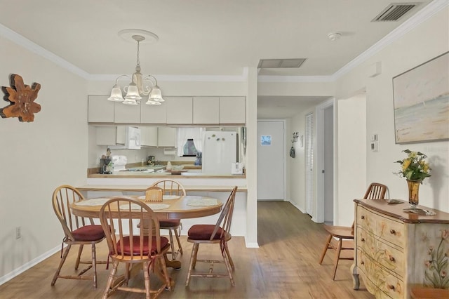 dining area featuring crown molding, an inviting chandelier, and light wood-type flooring