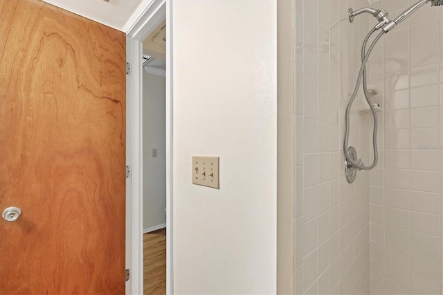 bathroom featuring hardwood / wood-style flooring and a tile shower