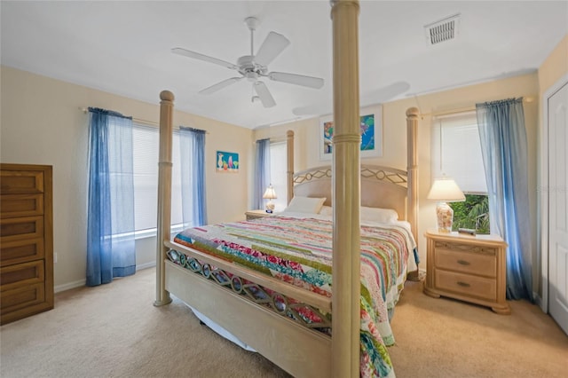 bedroom with ceiling fan, multiple windows, and light carpet