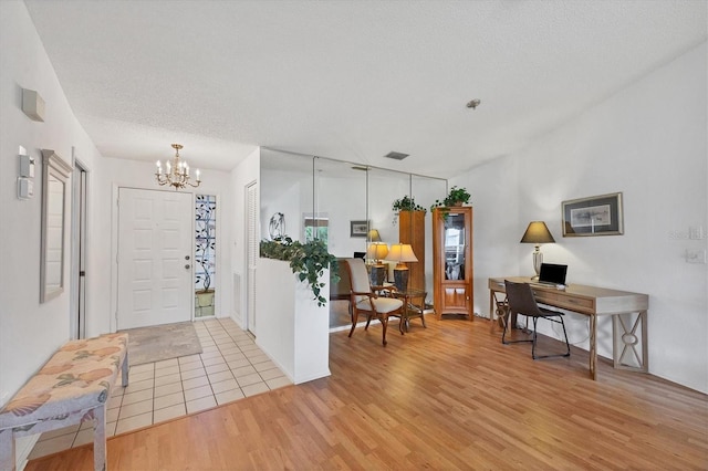 entryway featuring light hardwood / wood-style floors, a textured ceiling, and a notable chandelier