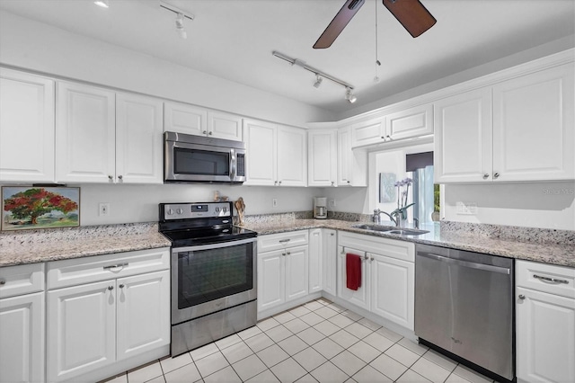 kitchen with appliances with stainless steel finishes, white cabinetry, sink, light stone counters, and ceiling fan