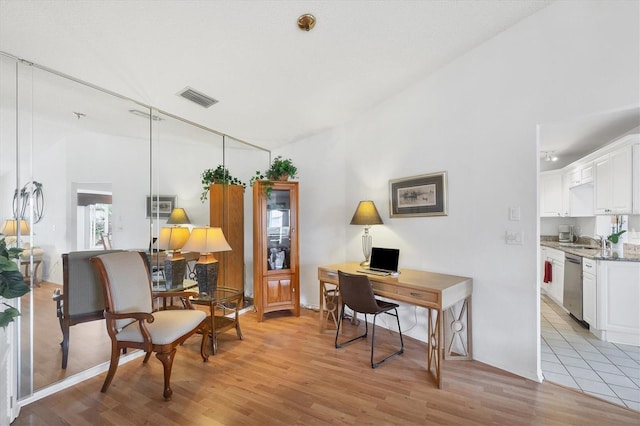 office space featuring sink, vaulted ceiling, and light hardwood / wood-style flooring