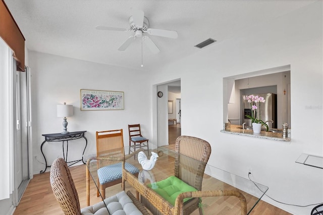 dining area featuring a textured ceiling, ceiling fan, and light hardwood / wood-style flooring