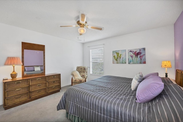 carpeted bedroom featuring ceiling fan and a textured ceiling