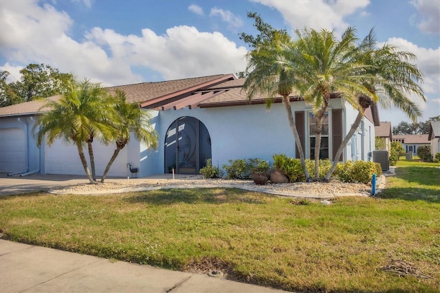 mediterranean / spanish-style house with a garage, cooling unit, and a front lawn