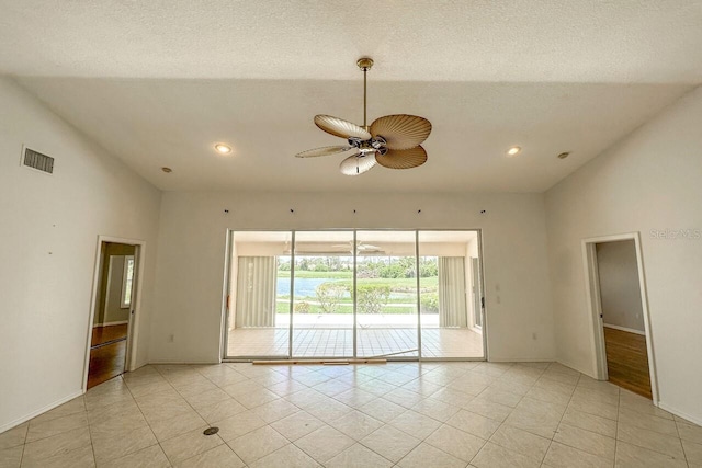 spare room with light tile patterned flooring, ceiling fan, vaulted ceiling, and a textured ceiling