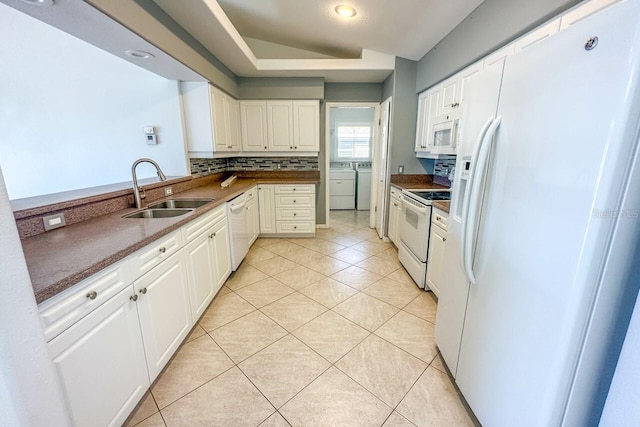 kitchen with white cabinetry, washer and dryer, sink, and white appliances