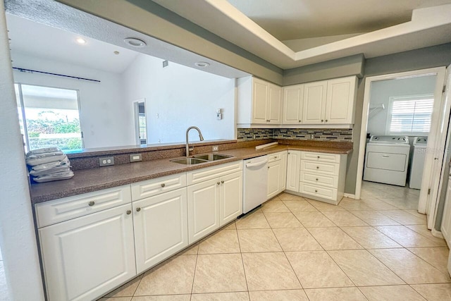 kitchen featuring sink, tasteful backsplash, white dishwasher, washing machine and dryer, and white cabinets