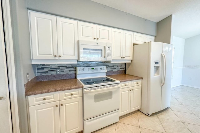 kitchen with white cabinetry, white appliances, light tile patterned flooring, and backsplash