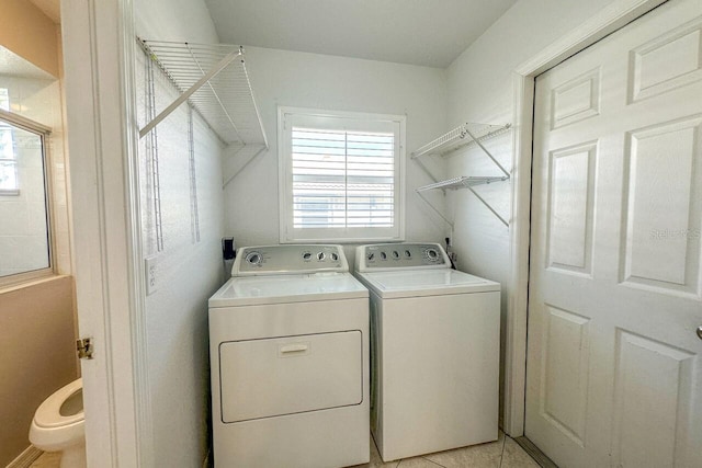 clothes washing area featuring light tile patterned floors and washer and clothes dryer