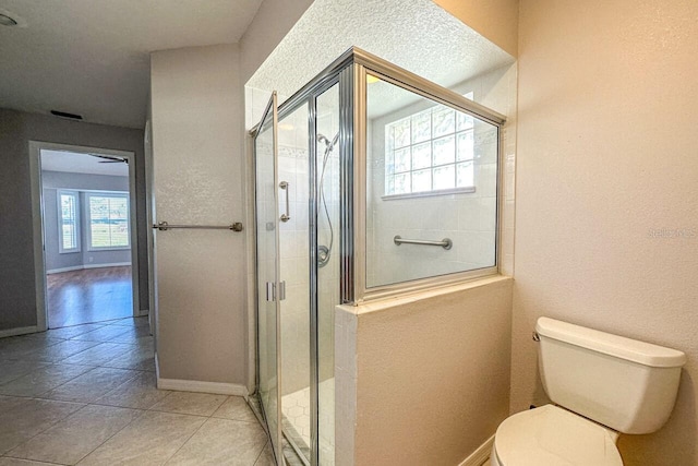 bathroom with tile patterned flooring, walk in shower, and toilet