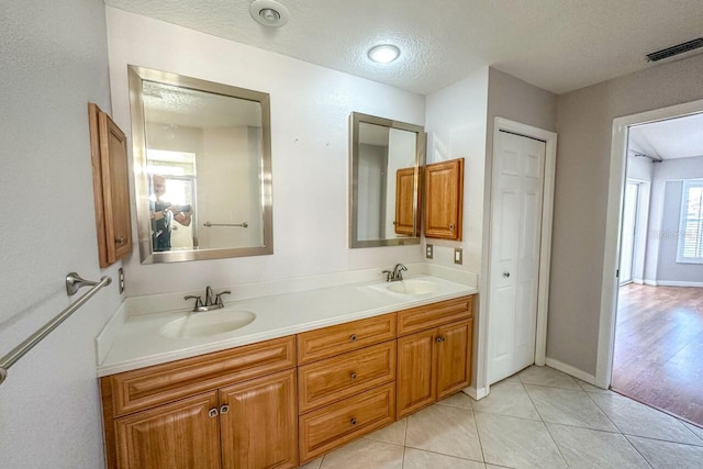 bathroom featuring tile patterned flooring, vanity, and a textured ceiling