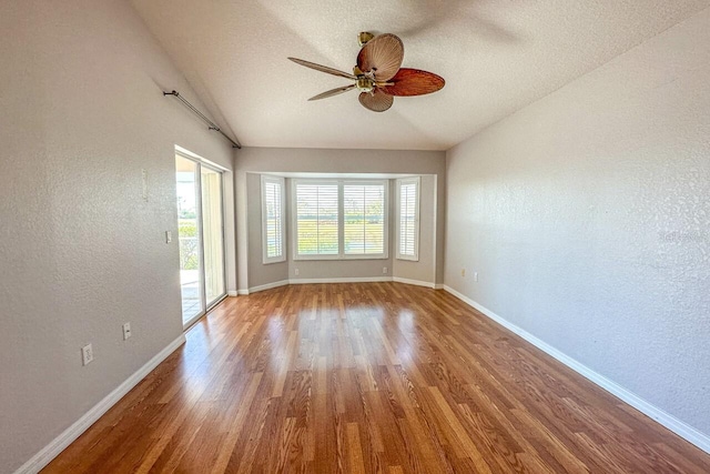 unfurnished room featuring wood-type flooring, vaulted ceiling, ceiling fan, and a textured ceiling