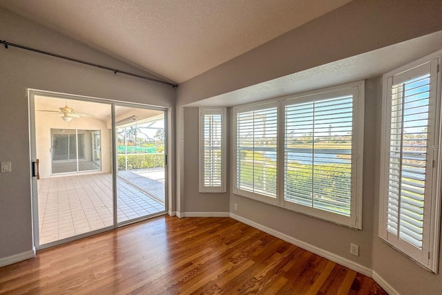 interior space featuring hardwood / wood-style flooring, lofted ceiling, and a textured ceiling