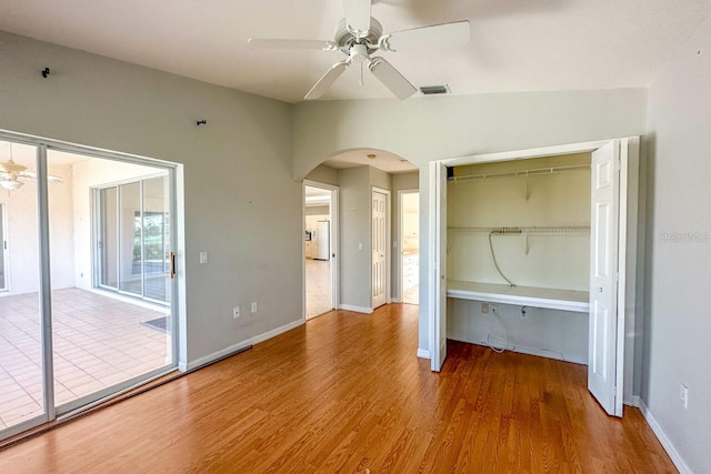 unfurnished bedroom featuring ceiling fan, access to exterior, hardwood / wood-style floors, and a closet