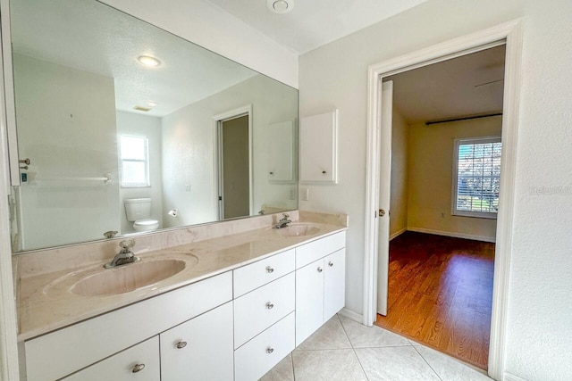 bathroom featuring tile patterned flooring, vanity, a wealth of natural light, and toilet