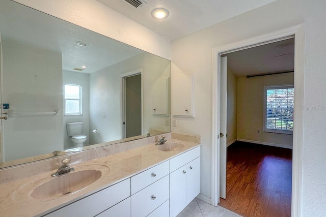 bathroom featuring vanity, hardwood / wood-style flooring, a textured ceiling, and toilet