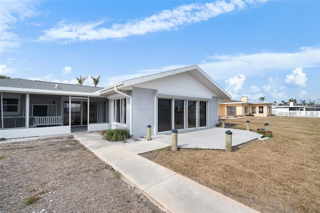 back of property featuring a patio, a yard, and a sunroom