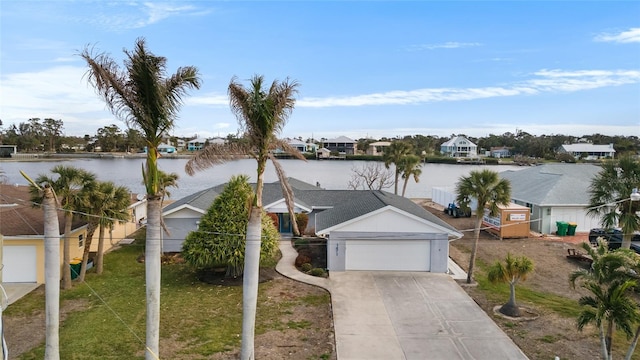 view of front of home with a garage, a front yard, and a water view