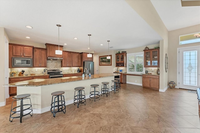 kitchen featuring stainless steel appliances, hanging light fixtures, a kitchen bar, and a large island