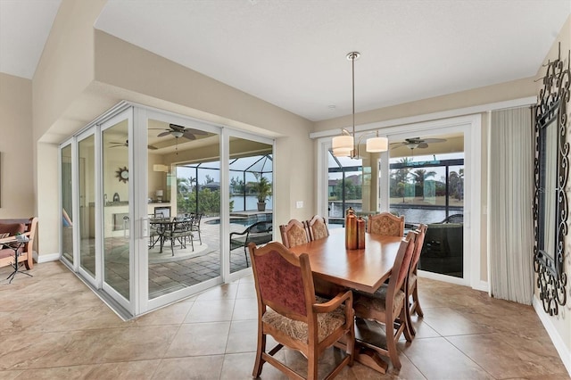 dining area with ceiling fan, a water view, and light tile patterned flooring