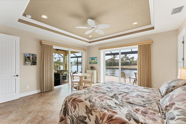 bedroom featuring ceiling fan, a raised ceiling, a water view, access to exterior, and ornamental molding