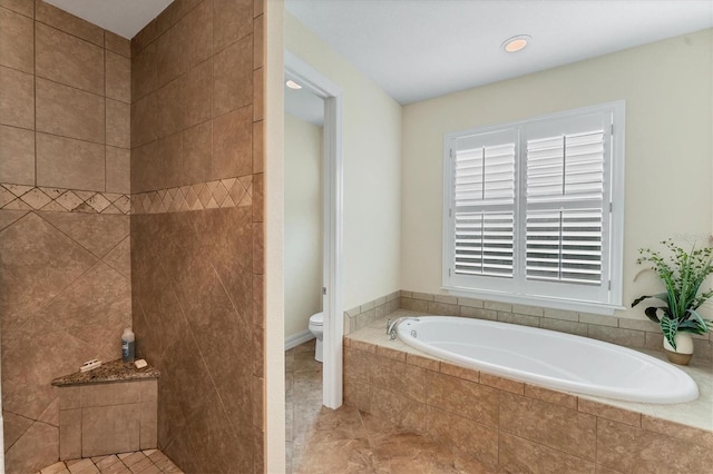 bathroom featuring toilet, tiled tub, and tile patterned flooring