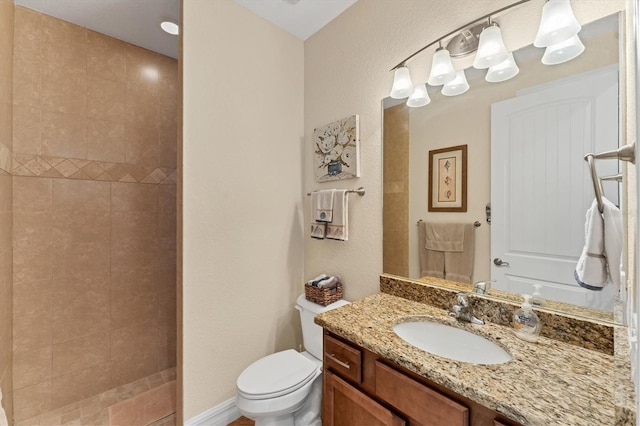 bathroom with tiled shower, vanity, and toilet