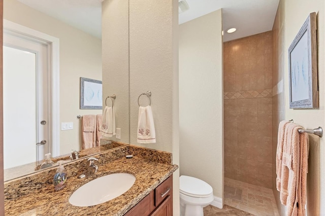 bathroom with vanity, toilet, tiled shower, and tile patterned flooring