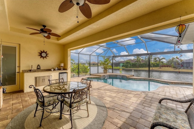 view of pool featuring a patio area, ceiling fan, glass enclosure, and a water view