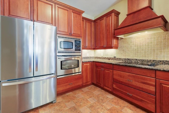 kitchen featuring custom exhaust hood, appliances with stainless steel finishes, decorative backsplash, and dark stone counters