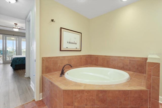 bathroom featuring tiled tub and ceiling fan