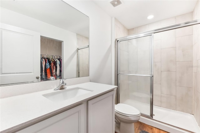 bathroom featuring hardwood / wood-style flooring, vanity, toilet, and walk in shower