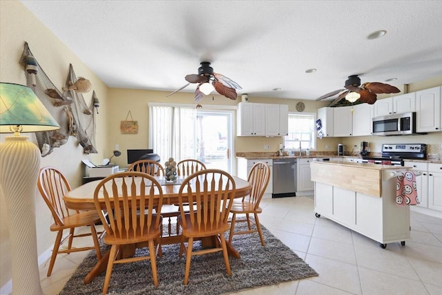 tiled dining room with a textured ceiling and ceiling fan